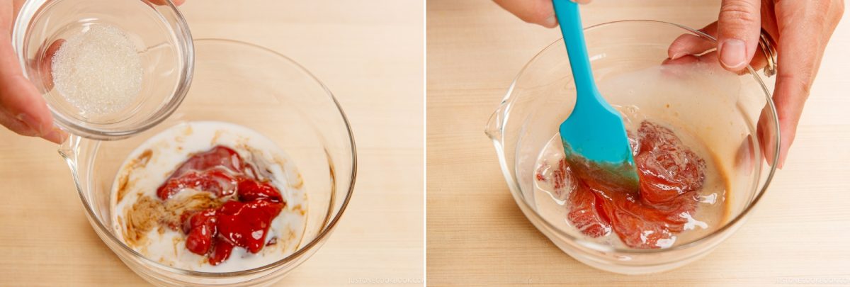 A hand pours sugar into a glass bowl containing napolitan sauce and milk, then uses a blue spatula to stir the ingredients together.