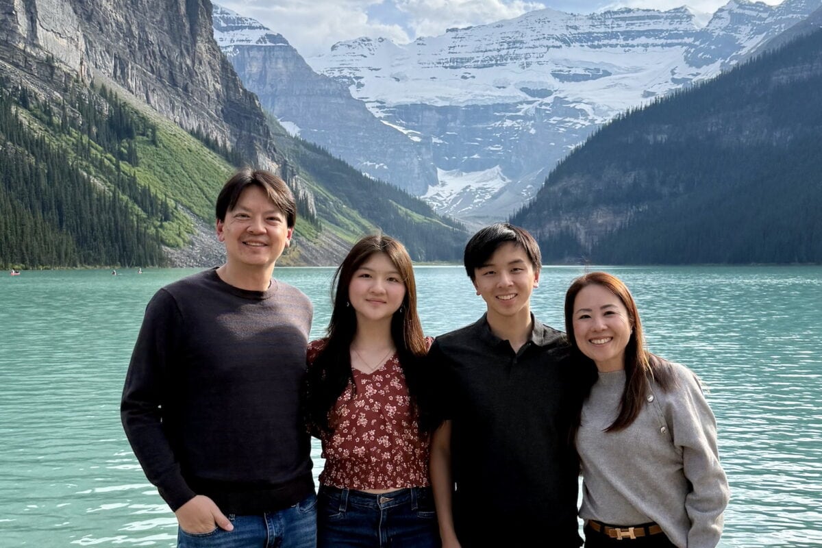 Vibrant family photo by a stunning glacier lake with mountains and snow-capped peaks in the background, showcasing a scenic outdoor destination.