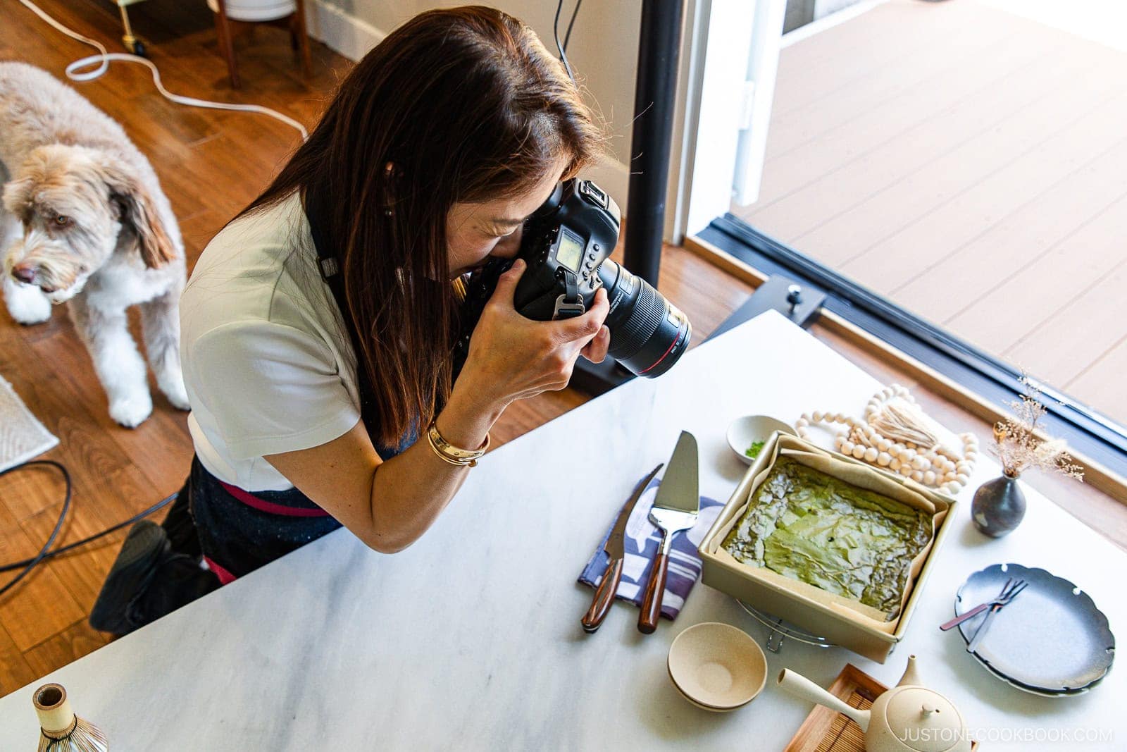 Vegan spinach lasagna on a white marble countertop with kitchen utensils and decorations, photographed by a food blogger for Just One Cookbook.