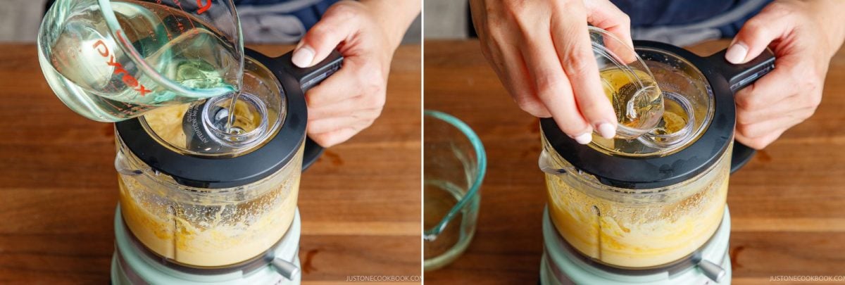 Two images show hands making a mayo in a food processor. In the first, oil is poured from a measuring cup. In the second, a spoon adds an ingredient through the lid opening. Both are on a wooden surface.