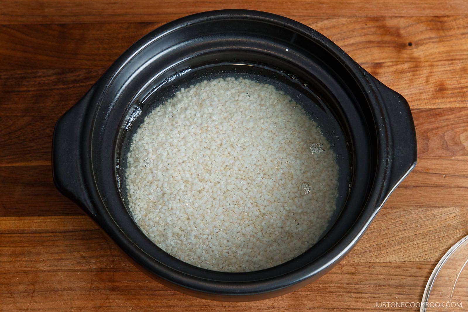 Raw brown rice soaking in a black pot filled with water.