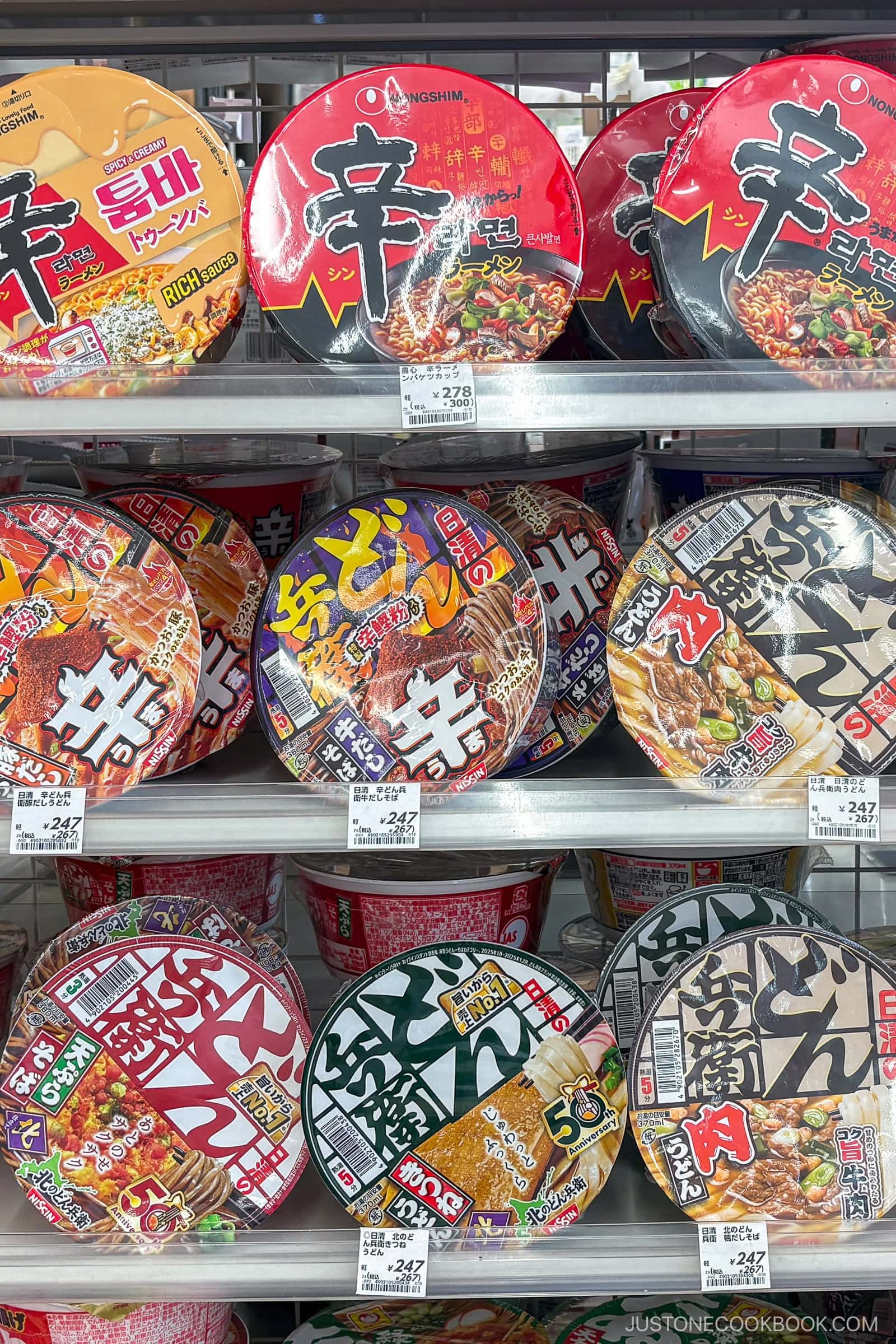 A retail shelf displaying various Nongshim and Donbei instant noodle bowls with Japanese price tags, perfect for those seeking new instant ramen hacks.