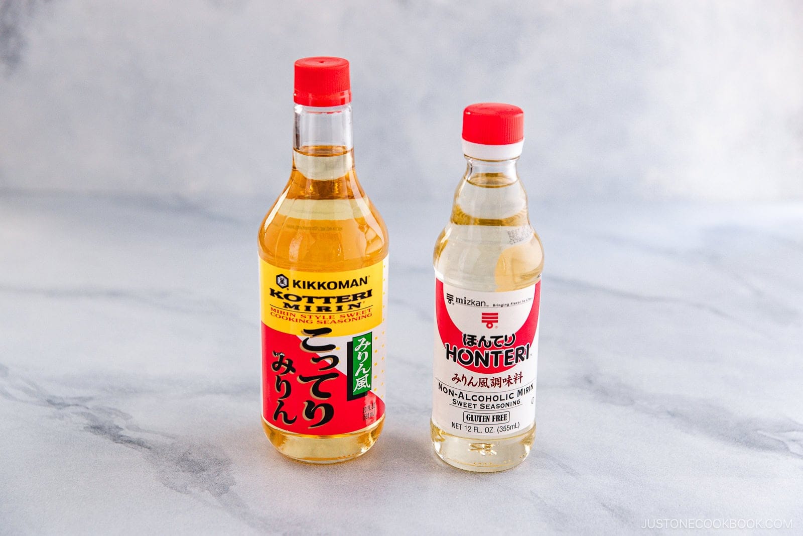 Two bottles of mirin stand side by side on a light gray surface—perfect for exploring Sake vs Mirin: Key Differences and How to Use Them. The left is Kikkoman Kotteri Mirin; the right is Honteri non-alcoholic mirin.