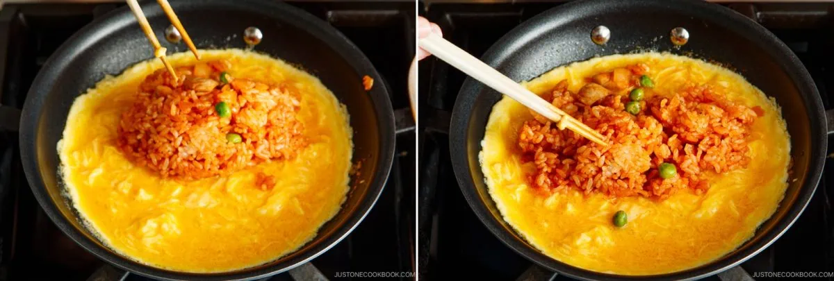 A frying pan with beaten eggs cooking for omurice, topped with tomato fried rice being placed and shaped using chopsticks.