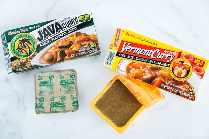 Two boxes of Japanese curry roux, Java Curry (medium hot) and Vermont Curry (mild), with an opened Java Curry package showing its brown curry block on a white background&mdash;perfect for preparing authentic Japanese chicken curry at home.