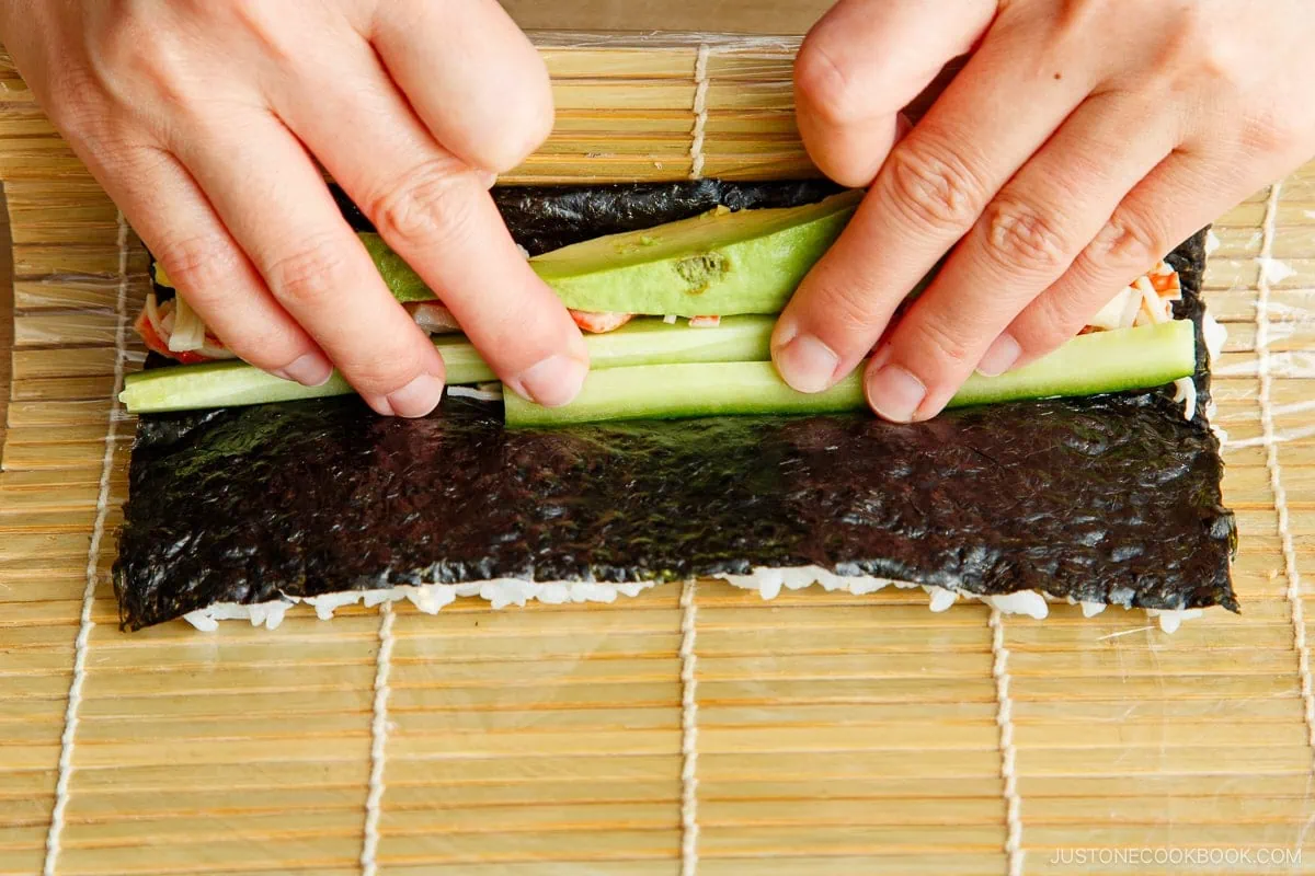 Carefully roll the nori and rice over the filling.