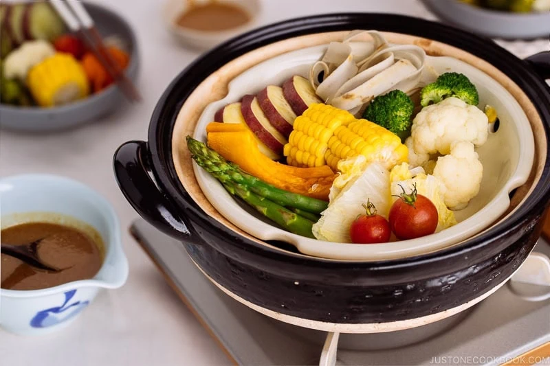 Steamed vegetables on donabe steamer along with dipping sauce.