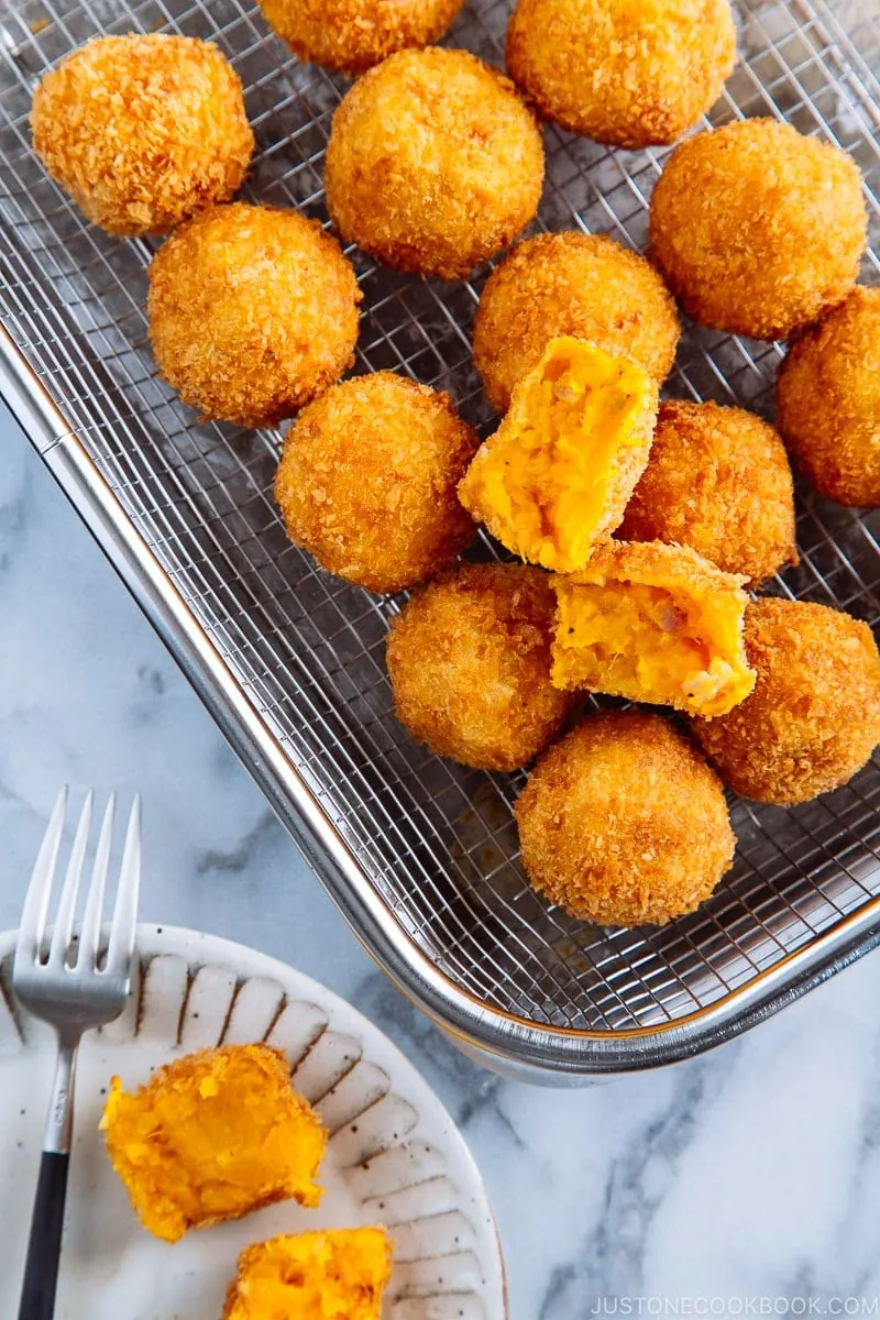 A stainless steel wire rack containing round Kabocha Croquettes (Korokke).
