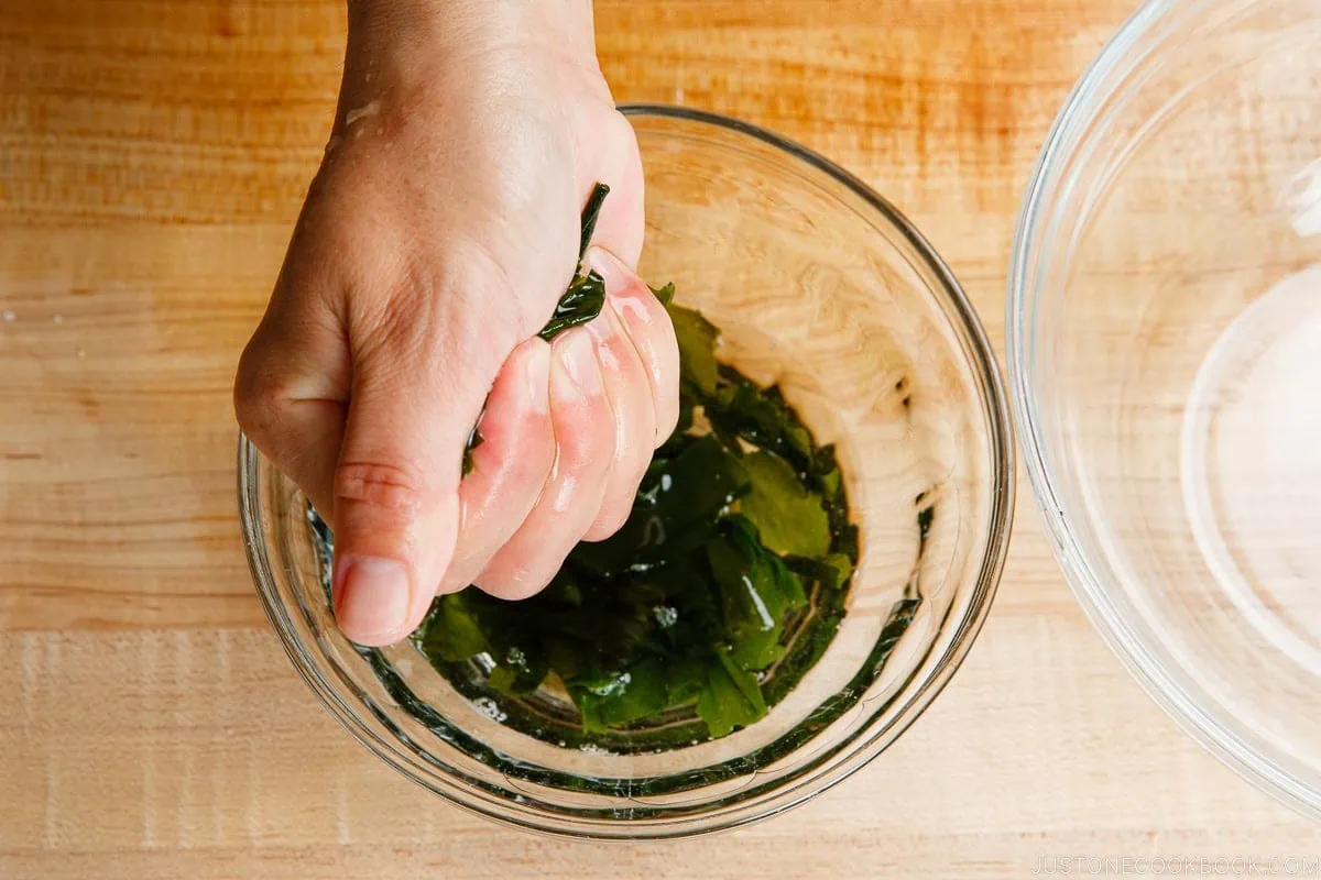 Squeeze water out from the rehydrated wakame seaweed.