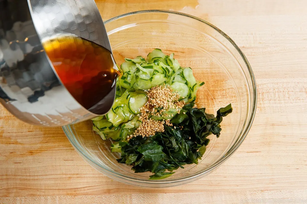 Pouring the seasonings to the cucumbers.