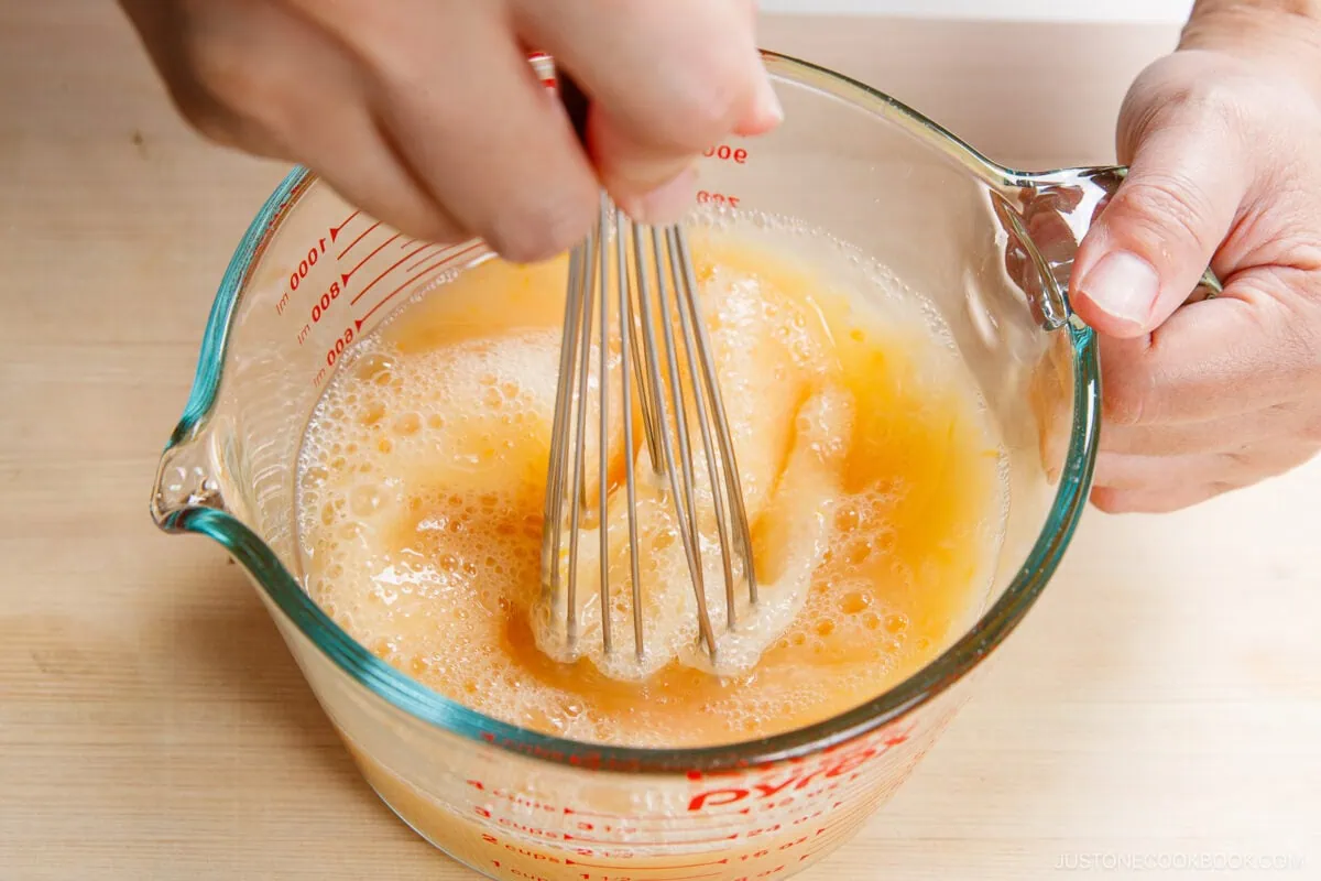 Whisking eggs for Chawanmushi in a glass bowl, preparing a traditional Japanese savory egg custard dish.