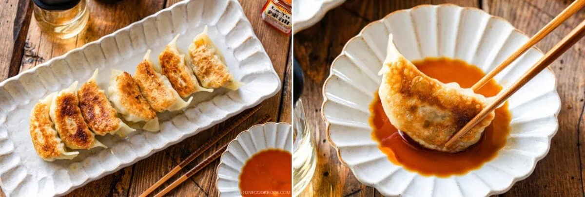 A plate of six golden-brown pan-fried dumplings, made from a classic Gyoza Recipe, sits next to a small dish of dipping sauce; on the right, chopsticks hold one dipped dumpling, all on a wooden table.